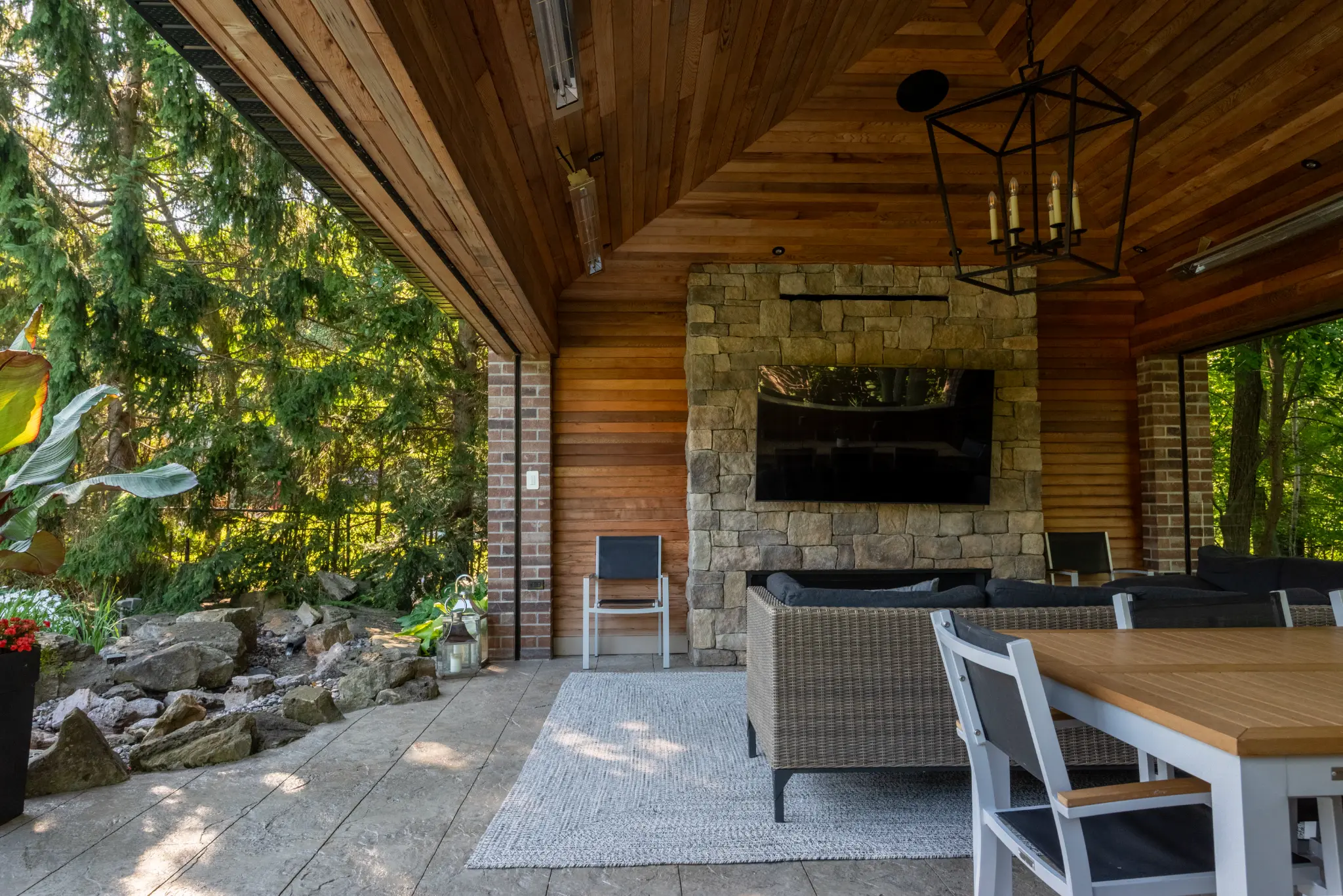 Covered outdoor living area opening onto landscaped greenery