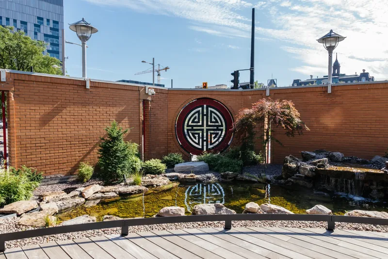 Pond and planting in front of the brick wall with a circular Chinese medallion