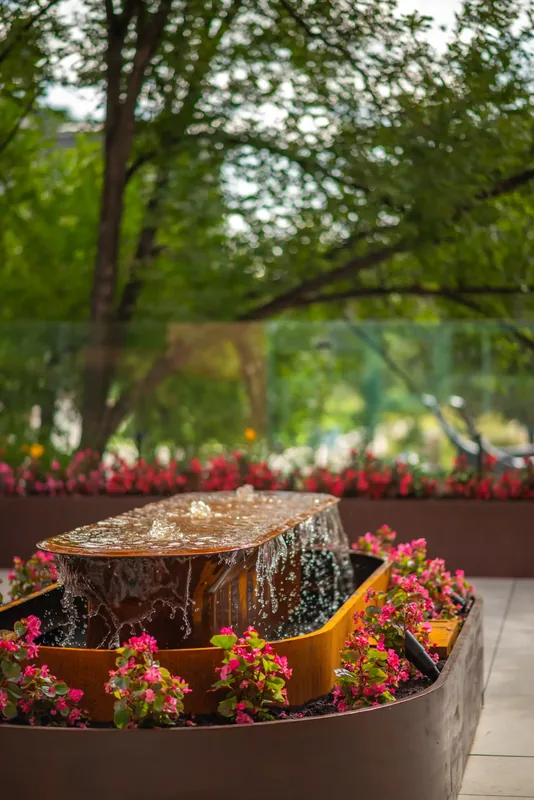 Steel water feature surrounded by flowers on the terrace