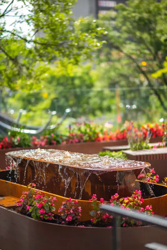 Steel water feature surrounded by flowers on the terrace