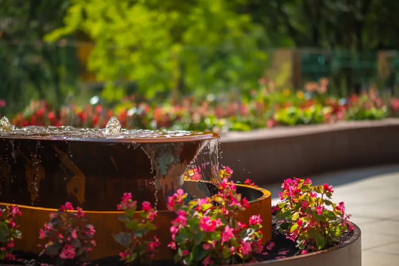 Steel water feature surrounded by flowers on the terrace
