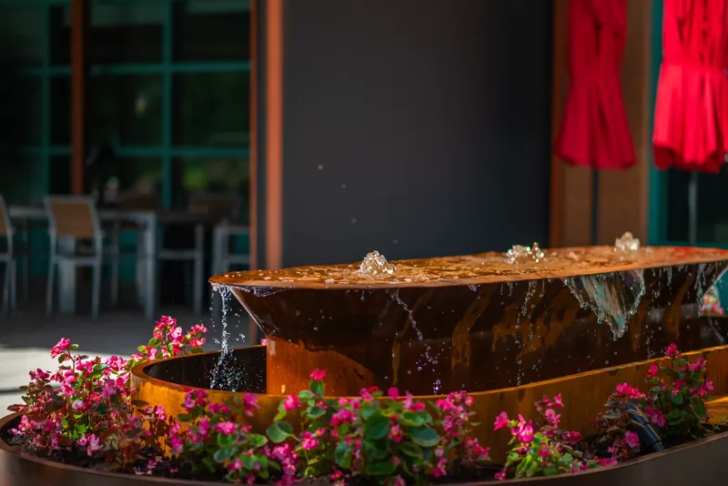 Steel water feature surrounded by flowers on the terrace