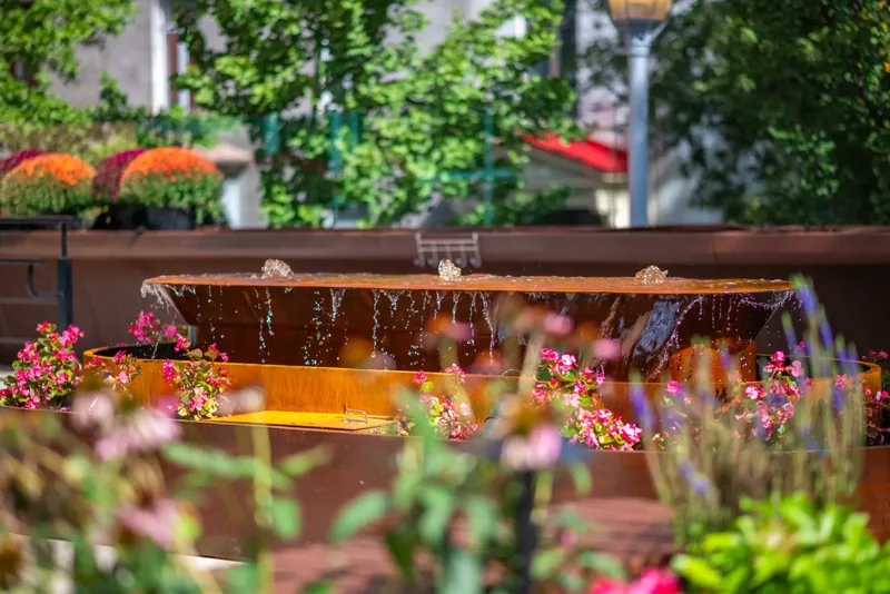 Steel water feature surrounded by flowers on the terrace