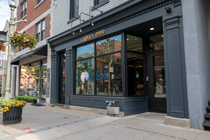 Street view of the storefront with flower planters, hanging baskets, and full-height display windows