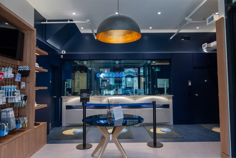 Client floor leading to a glass teller enclosure with a backlit Globex 2000 sign, beneath a copper-lined dome pendant