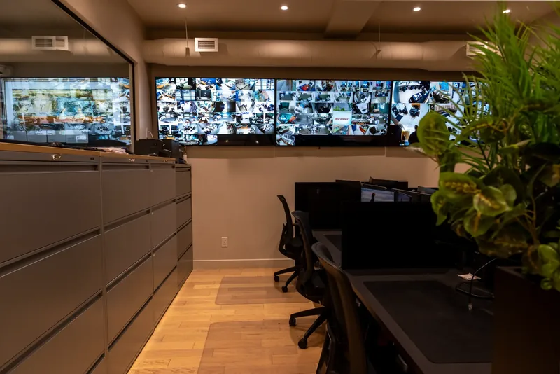 Wall of monitors above lateral file cabinets in the operations room