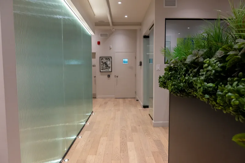 Corridor lined with a backlit ribbed glass partition and light oak flooring