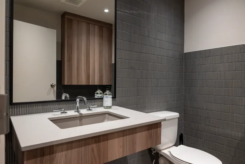 Washroom with a wood vanity, a white counter, and charcoal tile