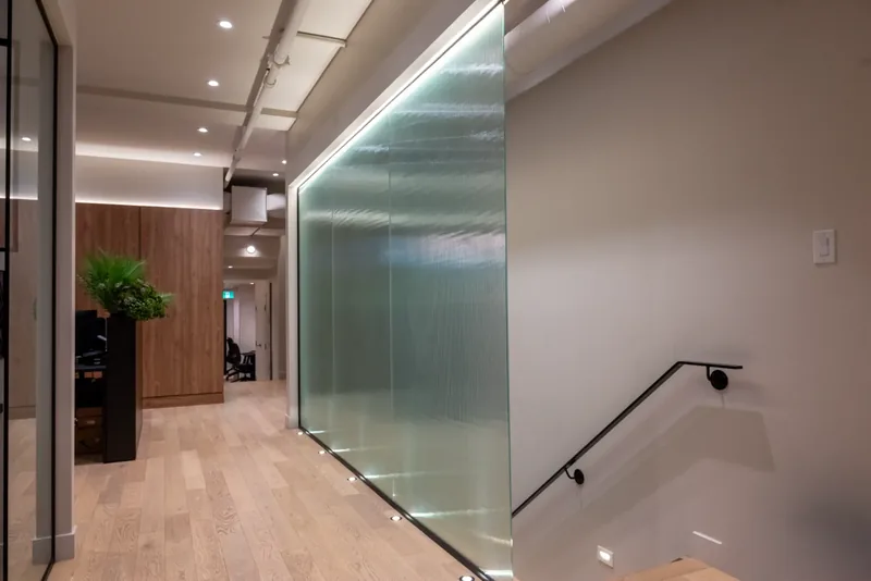 Ribbed glass guard around the stair opening, with a slim black handrail