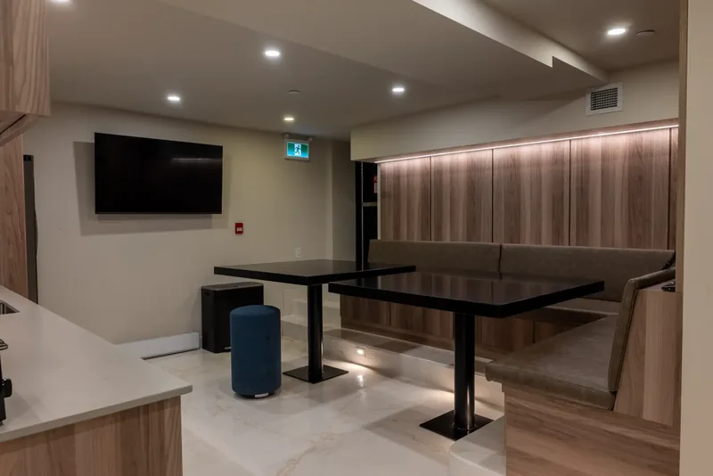 Staff lounge with banquette seating, black tables, and wood panelling with concealed lighting