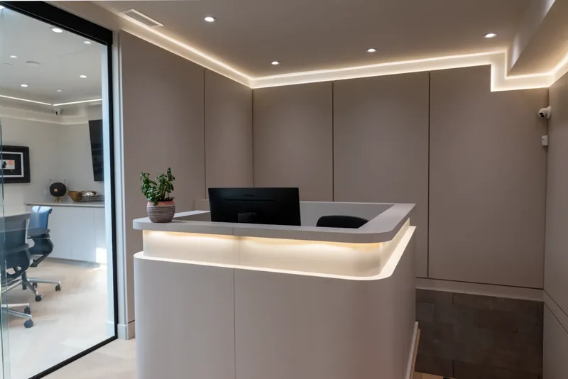 Reception area with an illuminated curved desk, full-height panelling, and cove lighting