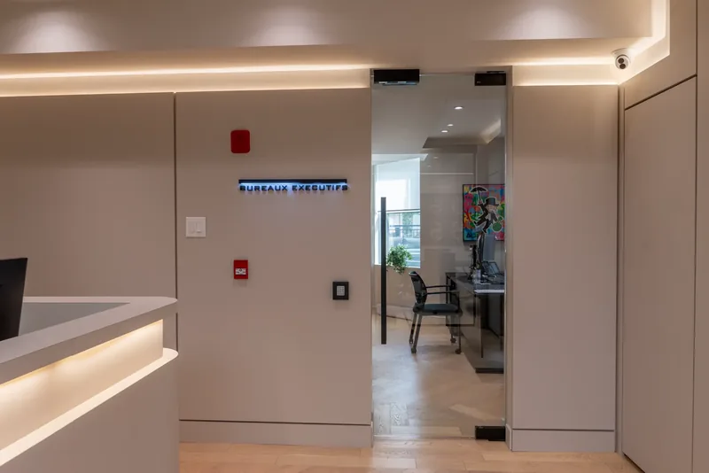 Entry to the executive offices, with a backlit Bureaux exécutifs sign and a glass door