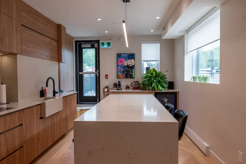 Kitchen with a long stone island, wood cabinetry, and a window above the counter