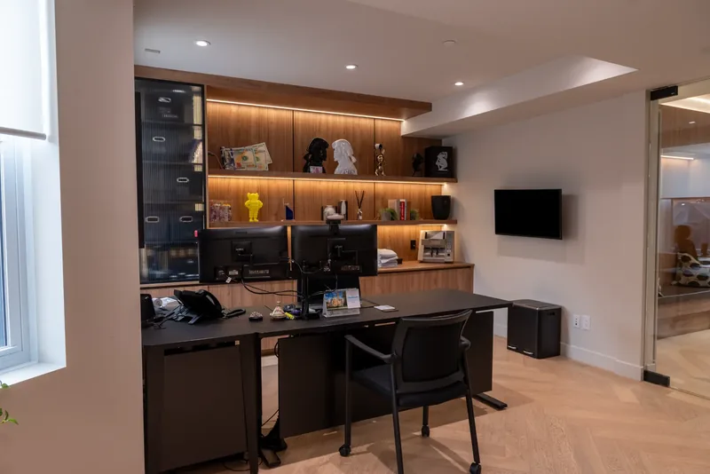 Executive office with a dark desk and wood millwork with lit display shelves