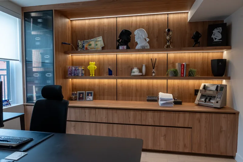 Close view of lit display shelves and a wood credenza in an executive office