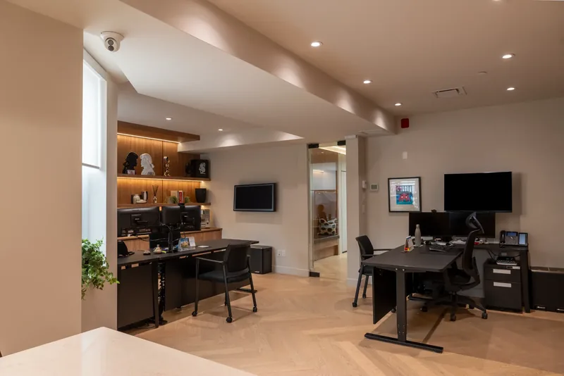 Open executive workspace with herringbone oak floors, dark desks, and lit millwork