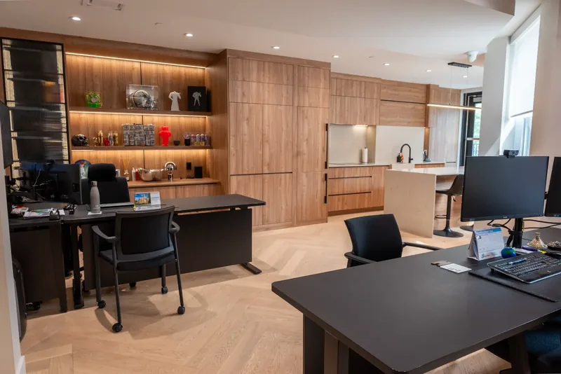 Executive workspace with dark desks, wood millwork, and a view through to the kitchen
