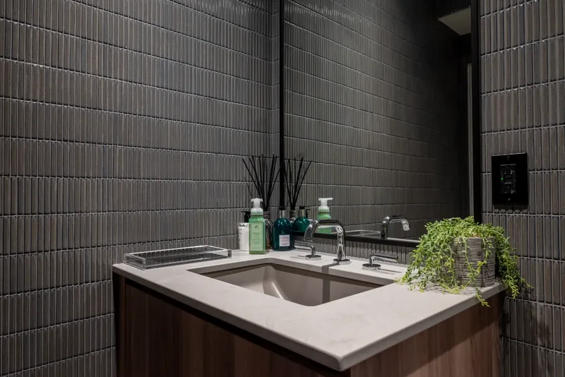 Washroom with charcoal stacked tile, a wood vanity, and an undermount sink