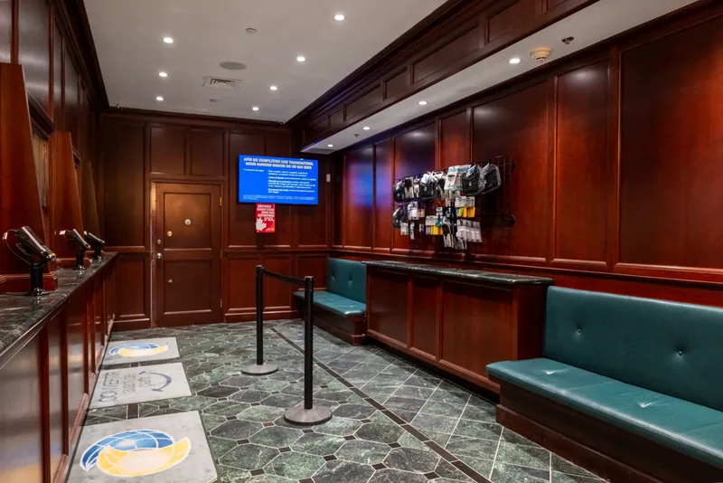 Waiting area with teal leather banquettes, panelled walls, and a green marble floor