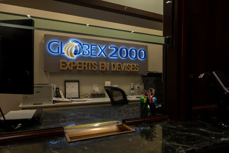 Backlit Globex 2000 sign seen through a teller window above a green marble counter