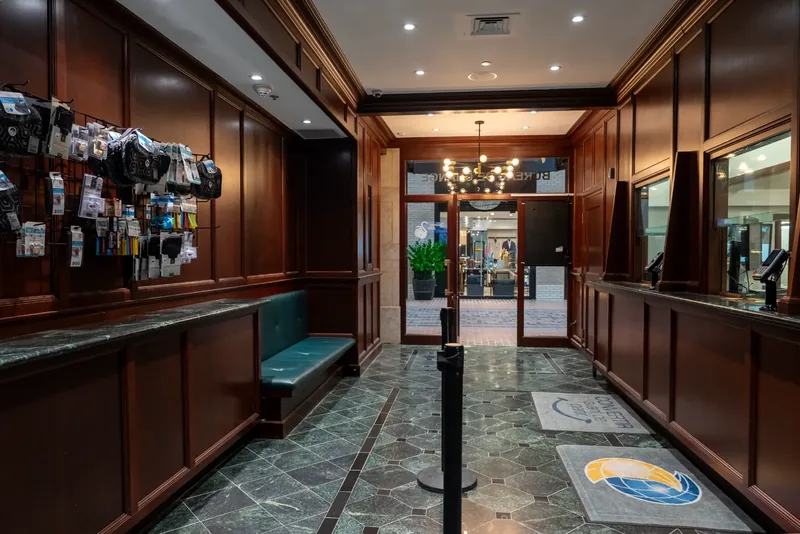Client hall with a leather banquette, a marble ledge, and teller windows leading to the entrance