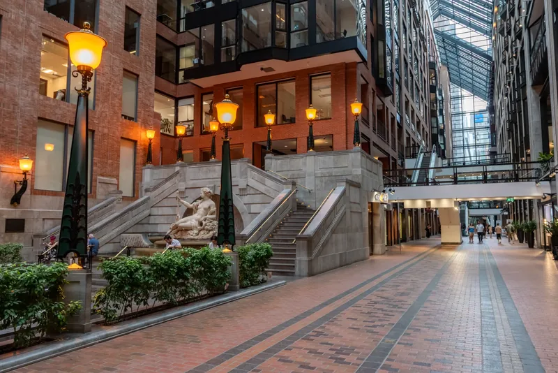 Grand stone staircase with a reclining sculpture, lanterns, and planters in the atrium