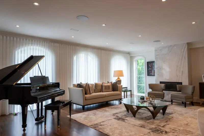 Living room with a grand piano, arched windows, and sheer drapery
