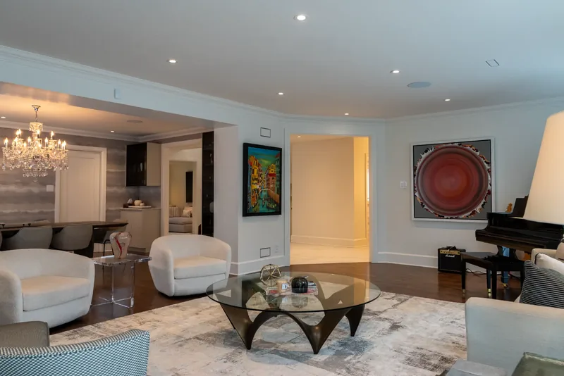 Open living and dining area with white swivel lounge chairs and a crystal chandelier