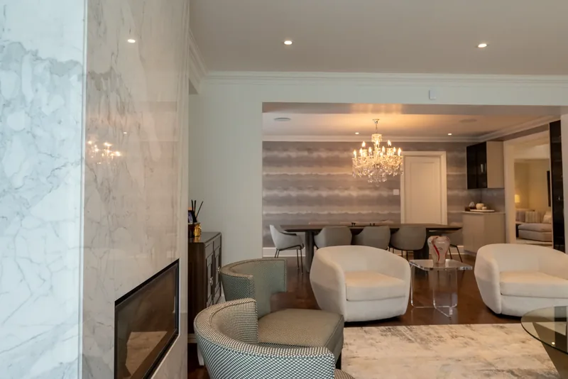 Open living and dining area with white swivel lounge chairs and a crystal chandelier