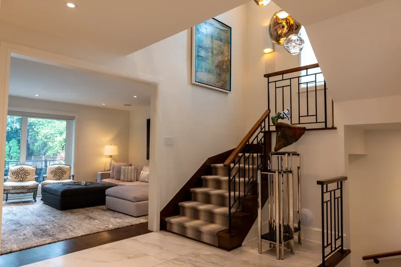 Open staircase with wood treads, a striped runner, and a black metal balustrade