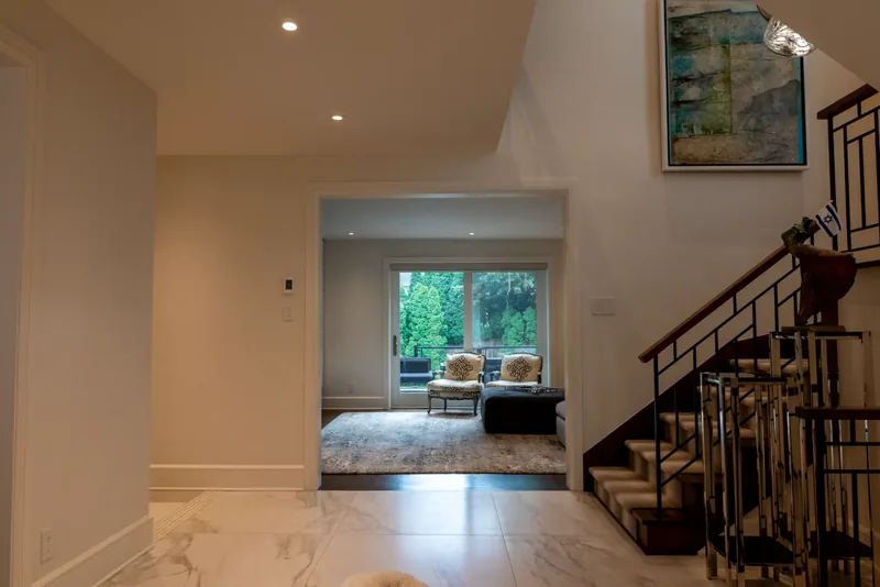 Open staircase with wood treads, a striped runner, and a black metal balustrade