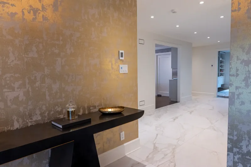 Foyer with a gold-leaf textured wall and a black floating console