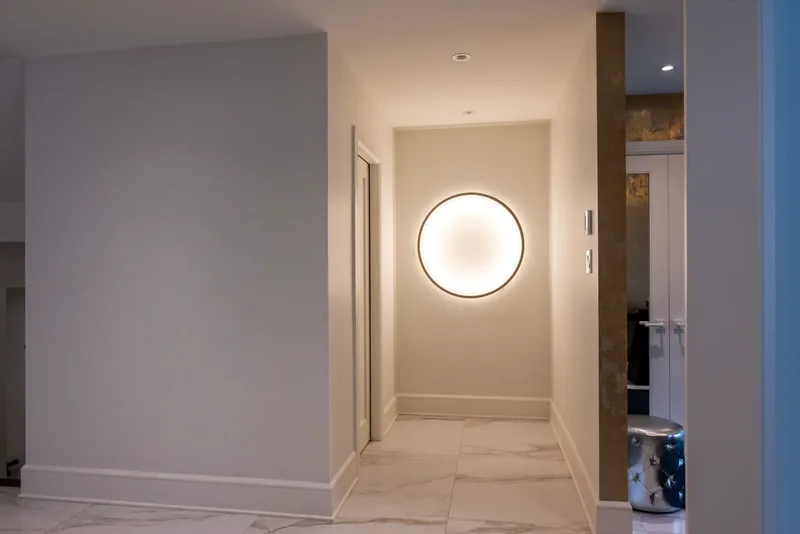 Hallway with marble-look floors and a round backlit wall light