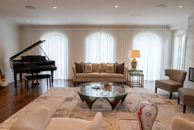 Living room with a grand piano, arched windows, and sheer drapery