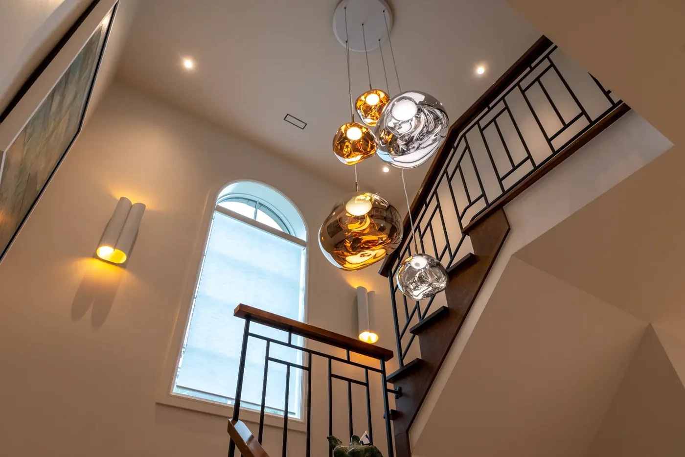 Cascade of glass globe pendants in the stairwell beneath an arched window