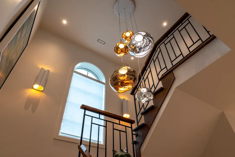 Cascade of glass globe pendants in the stairwell beneath an arched window