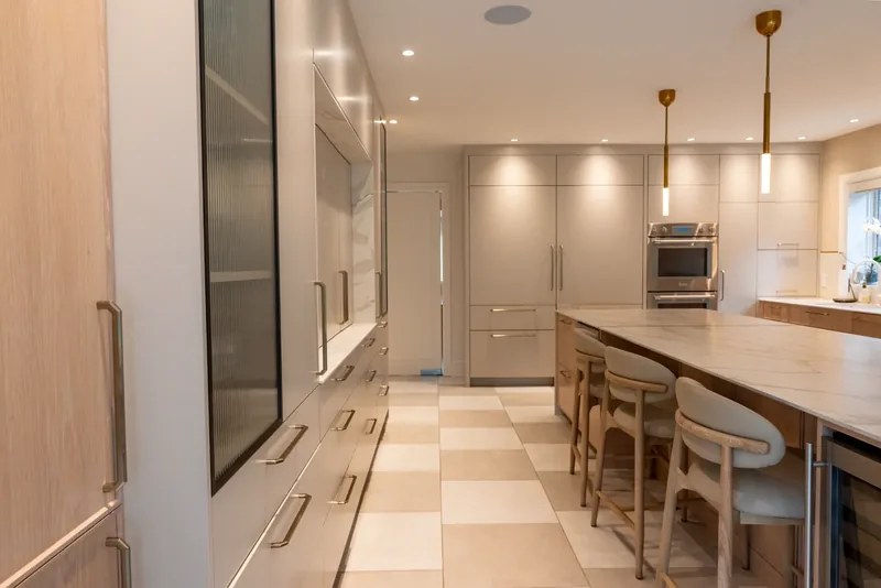 Kitchen with oak cabinetry, a marble-look waterfall island, and brass and glass pendants