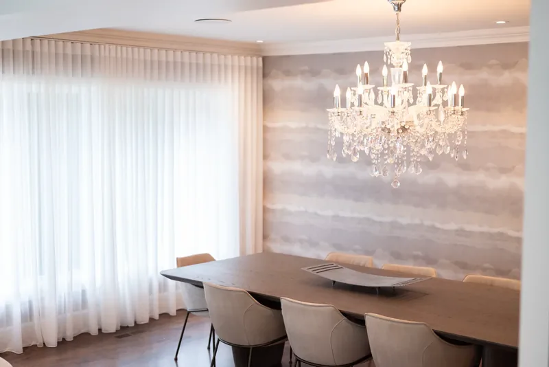 Dining room with a crystal chandelier, textured wallcovering, and a long table
