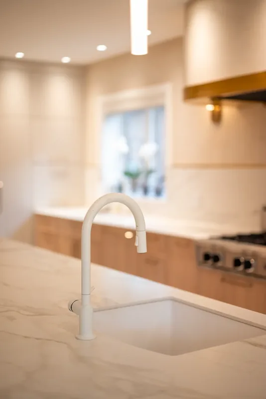 Undermount sink and white faucet set into the marble-look island