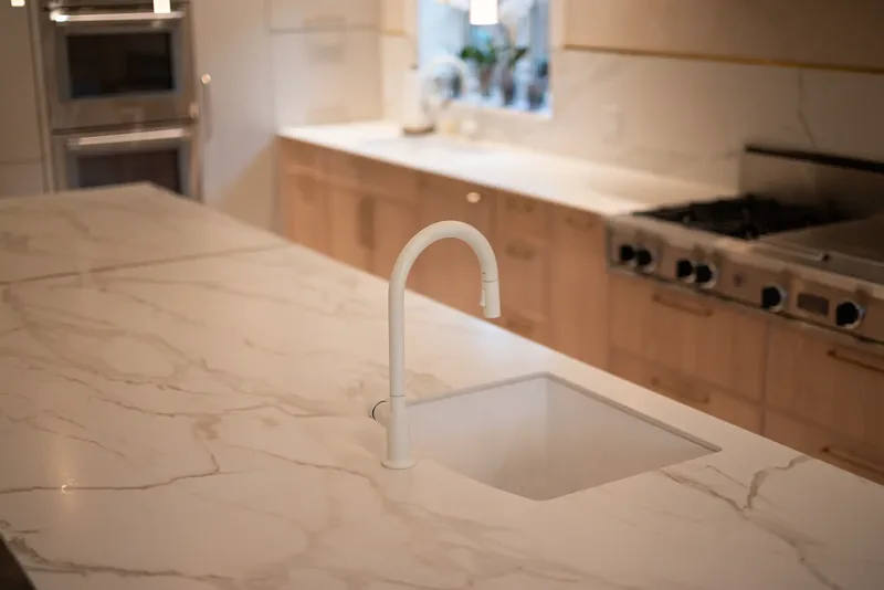 Undermount sink and white faucet set into the marble-look island