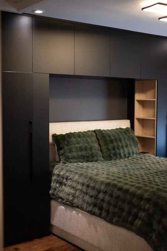 Bedroom with a dark built-in bed wall and integrated storage