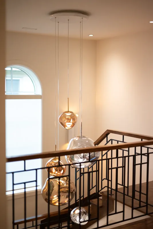Cascade of glass globe pendants in the stairwell beneath an arched window