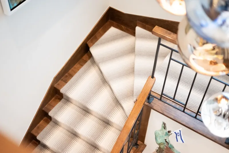 View from above of the staircase, its wood treads, and striped runner