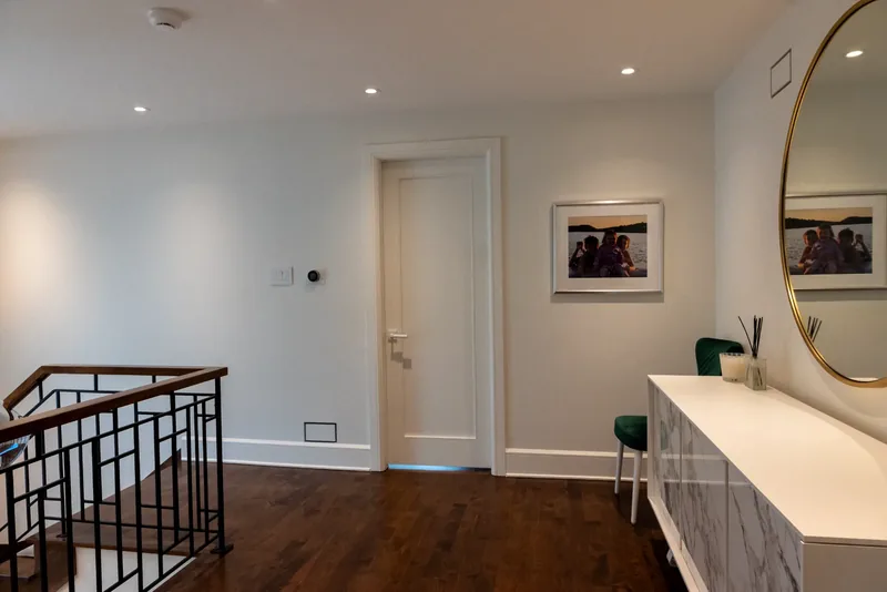 Landing with a round brass mirror, a marble-look console, and green velvet chairs