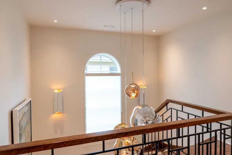 Upper landing with the metal balustrade, wall sconces, and glass pendants