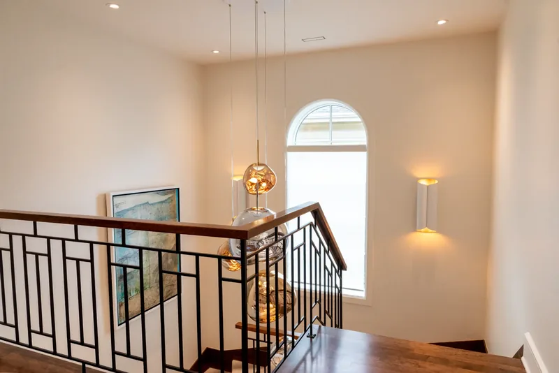 Upper landing with the metal balustrade, wall sconces, and glass pendants