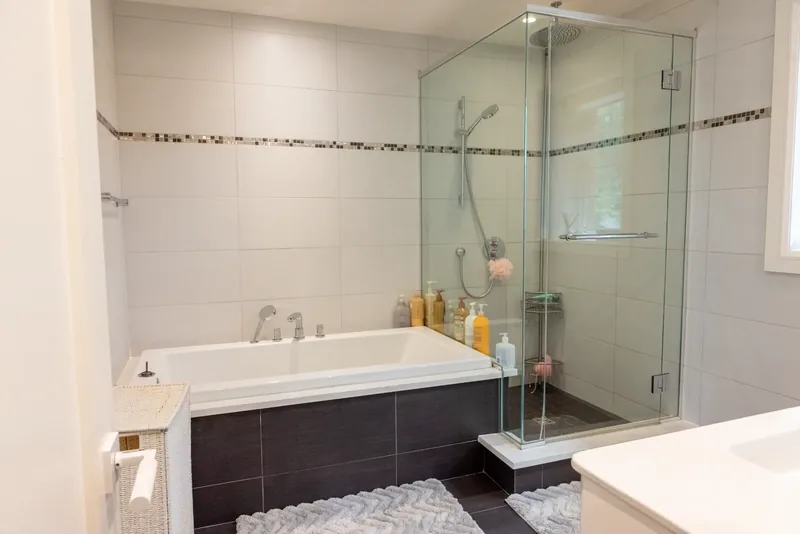Family bathroom with a soaking tub, a glass shower, and a mosaic accent band