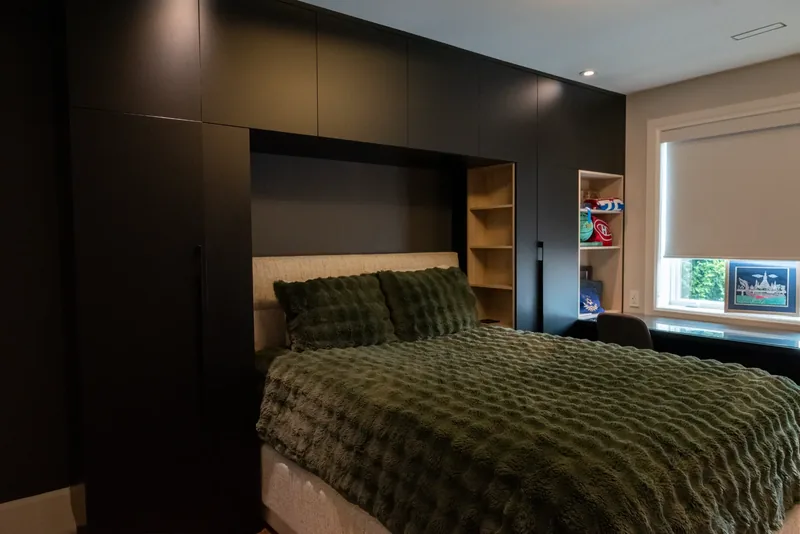 Bedroom with a dark built-in bed wall and integrated storage