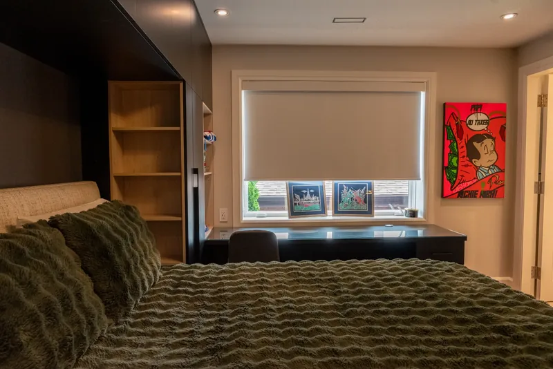 Bedroom with a dark built-in bed wall and integrated storage