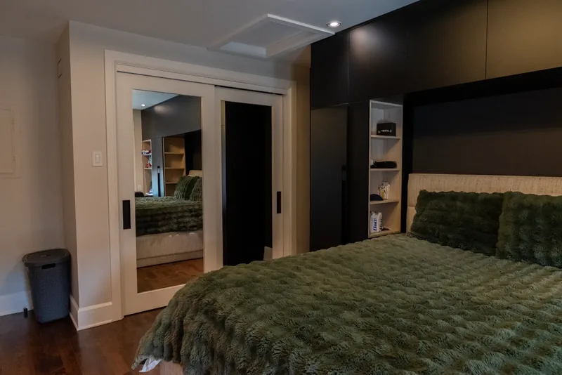 Bedroom with a dark built-in bed wall and integrated storage